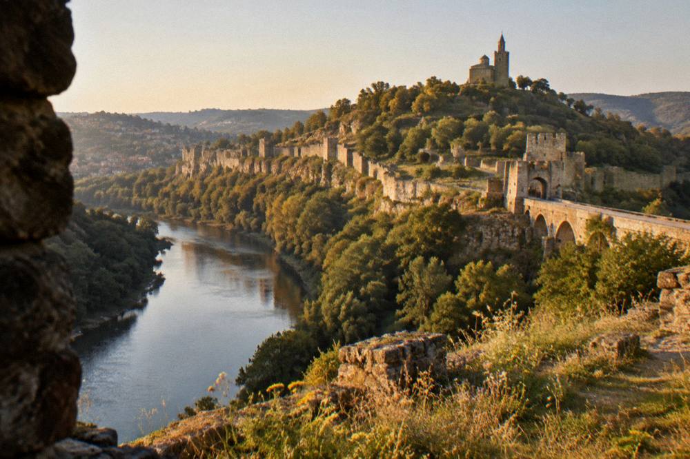 The stone walls of Tsarevets Fortress rising above the Yantra river in the evening light