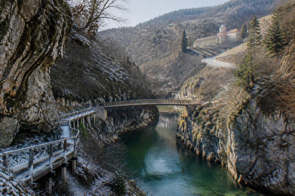 A country road winding through wooded hills towards a monastery building