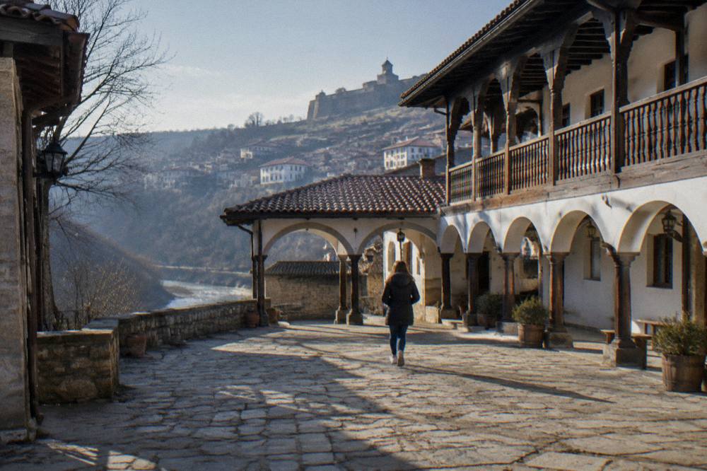 A stone monastery courtyard with an arched gallery in daylight