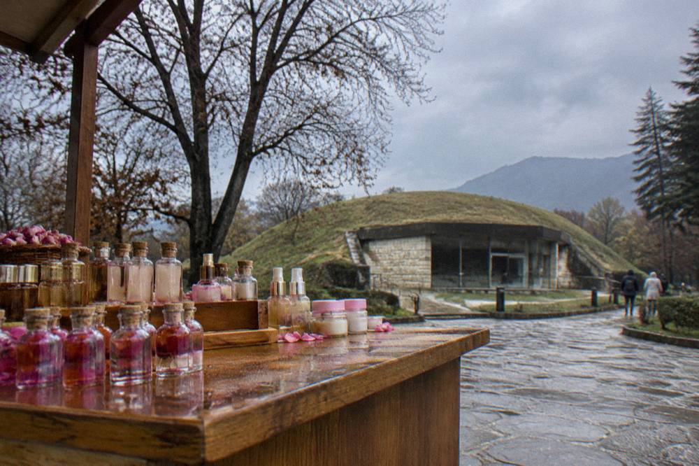 Small glass bottles of rose oil and rose cosmetics arranged on a wooden shop counter