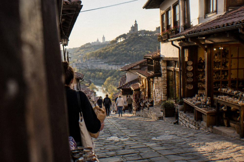 A shopper carrying a paper-wrapped purchase along a stone street at dusk in an old Bulgarian town
