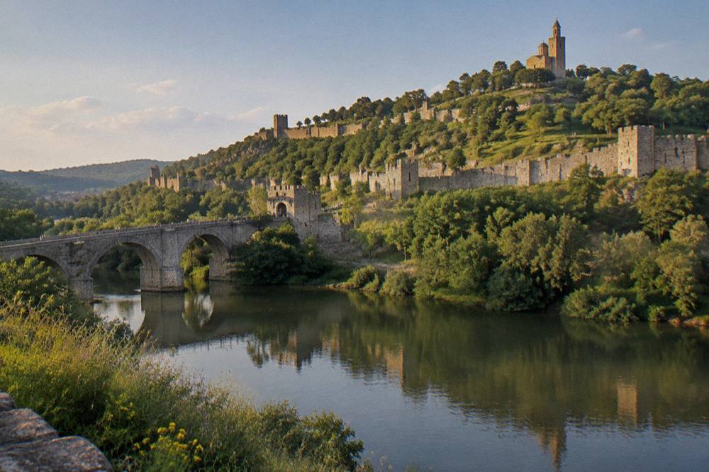 Stone walls and green slopes of Tsarevets Fortress seen from across the Yantra river