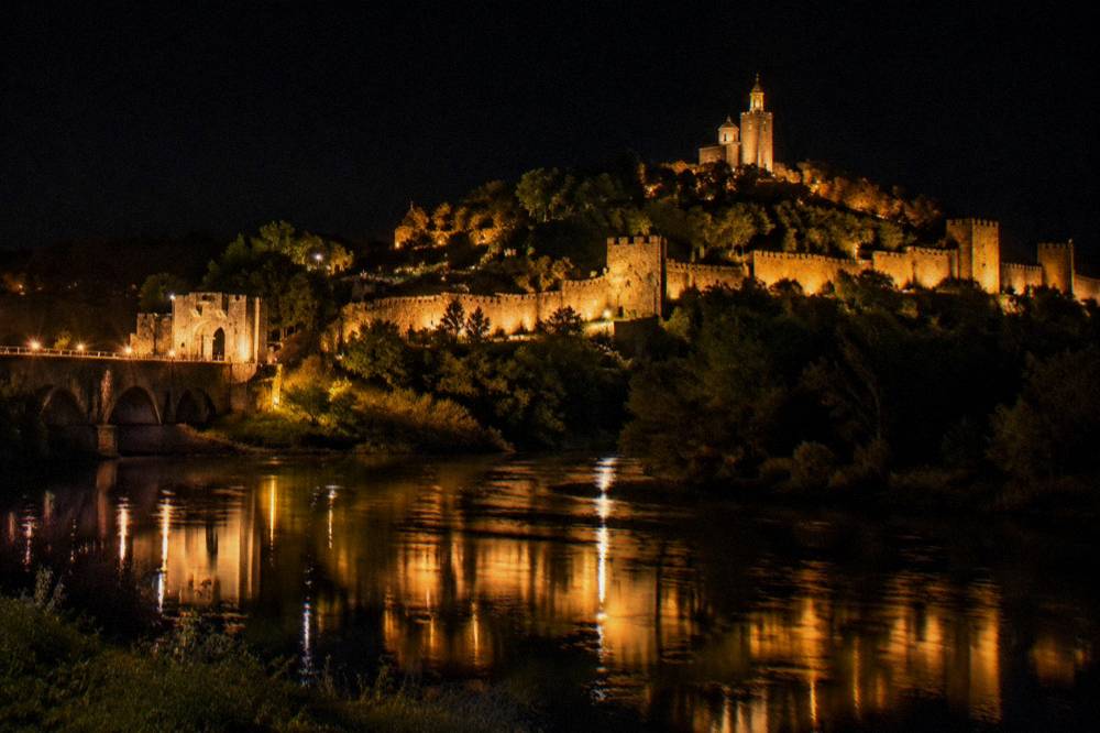 Illuminated Tsarevets Fortress walls reflected in the Yantra river at night