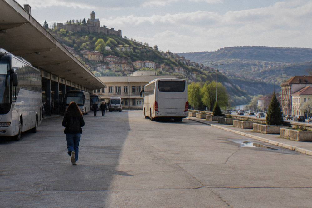 A regional coach pulling out of a bus station forecourt in a Bulgarian town
