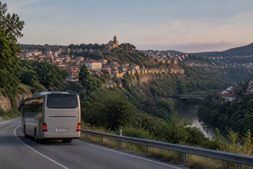 A coach travelling on a road through green hills towards a Bulgarian town