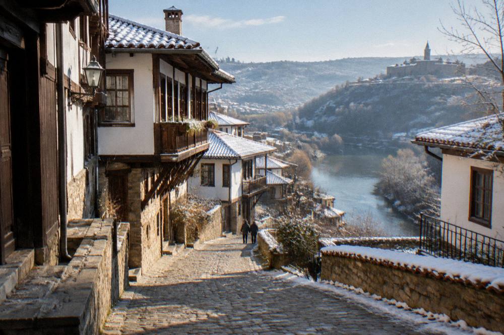 A steep cobbled street with traditional houses above a river bend in Veliko Tarnovo