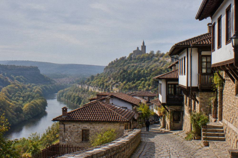 A village street with stone houses and a church tower in the hills above Veliko Tarnovo