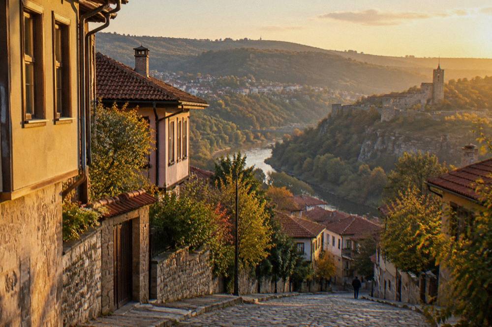 A country road curving through wooded hills toward a Bulgarian village with red roofs