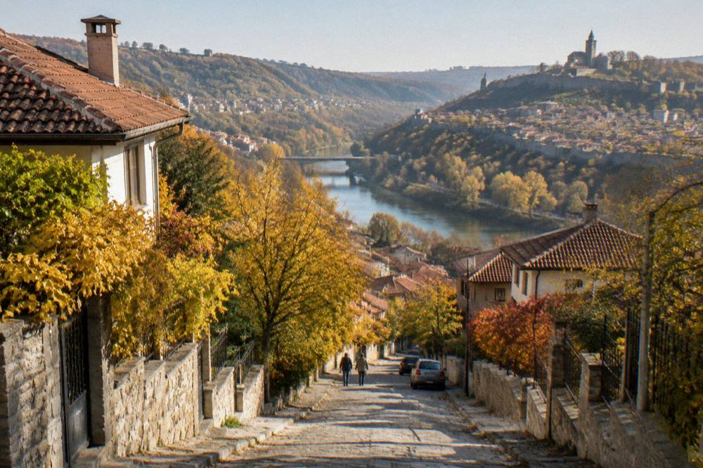 An autumn road lined with golden trees descending toward a river valley in Bulgaria
