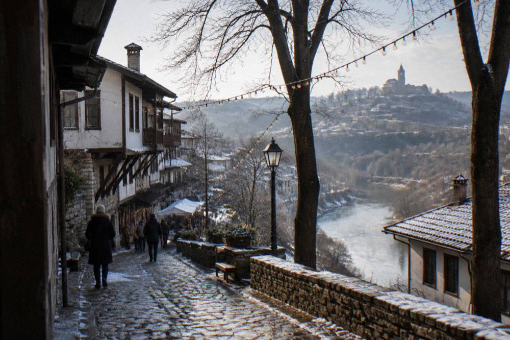 Festoon lights strung between bare winter trees above a market path