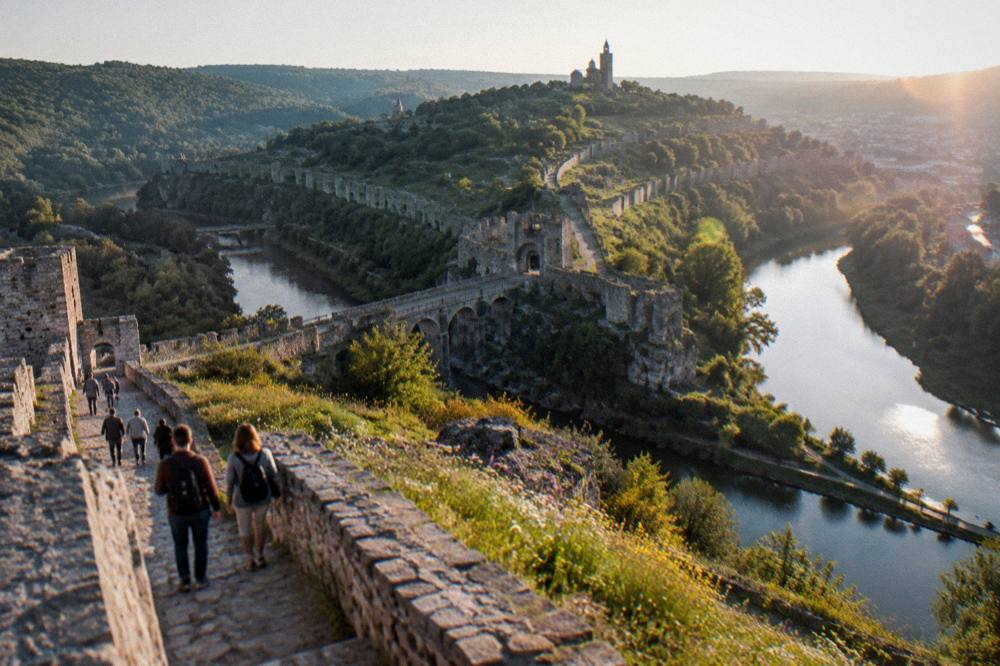 Visitors walking a path along restored fortress walls above the river
