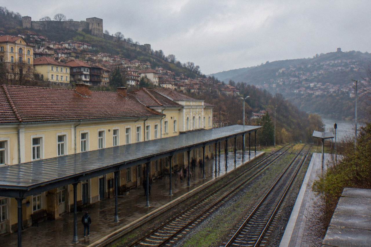 A railway station platform in a Bulgarian town with tracks running toward hills
