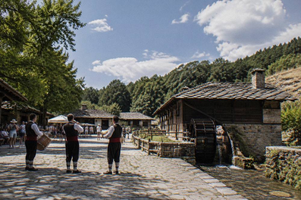 Musicians in traditional Bulgarian folk costume performing in a summer festival square