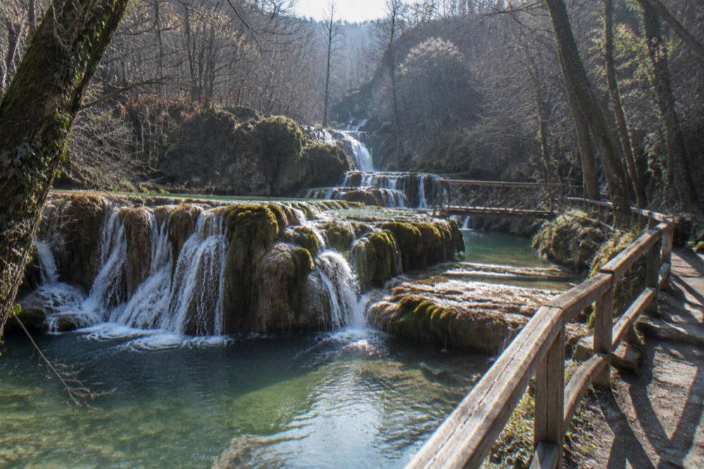 Waterfalls cascading over travertine ledges in a forested canyon near Veliko Tarnovo