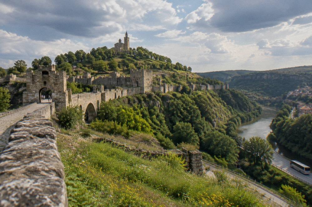 Long-distance coach on a road winding through wooded Balkan foothills