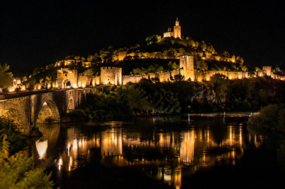 Illuminated fortress walls of Tsarevets reflected in the Yantra river at night
